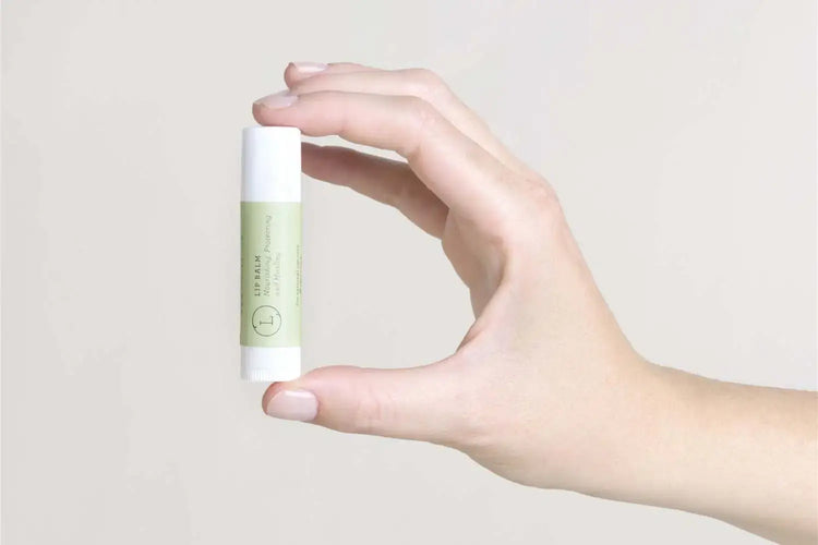 Hand holding a green skincare lip balm from the Soul Touch Massaging Set.