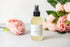 Massage drops bottle with CBD and eucalyptus oil, surrounded by fresh peonies for self-care.