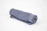 Rolled soft gray towel on a white background, ideal for spa and relaxation purposes.