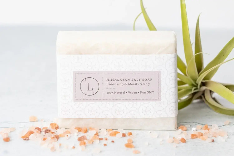 Himalayan salt soap bar with label, surrounded by pink salt and air plant, 100% natural and vegan.