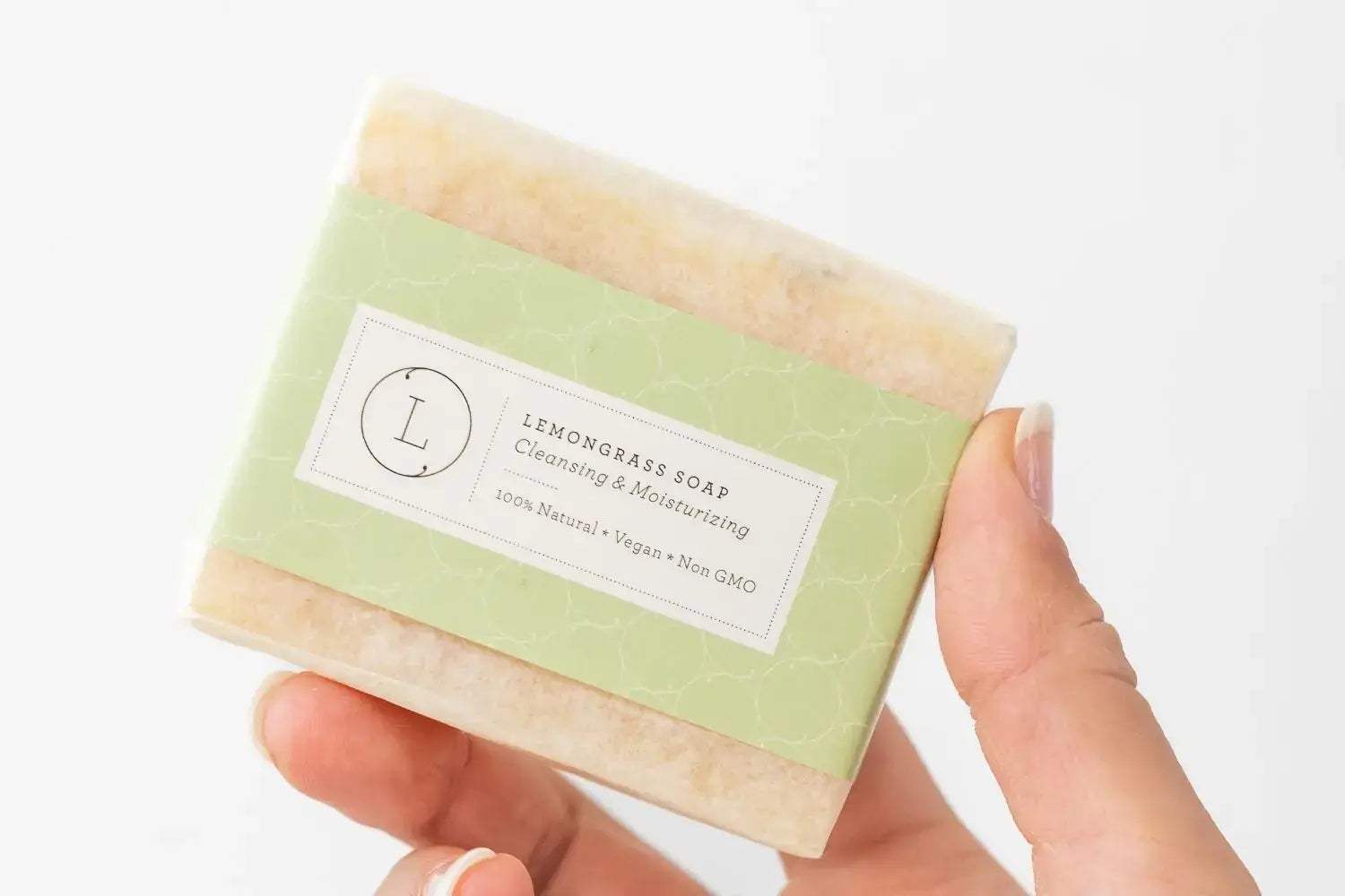 Handmade natural lemongrass soap bar, vegan and moisturizing, held in a hand with eco-friendly packaging.