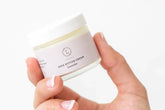 Hand holding a jar of Lavender Shea Butter Body Cream, showcasing its moisturizing properties and natural ingredients.